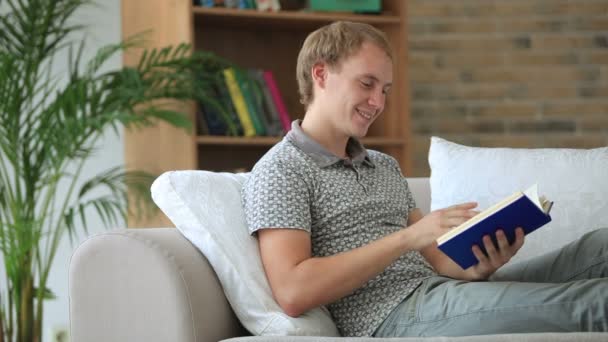 Mann entspannt sich auf Sofa beim Lesen — Stockvideo