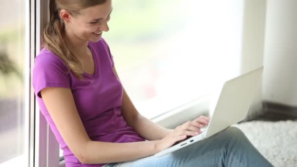 Cheerful girl sitting by window — Stock Video