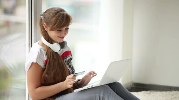 Chica en auriculares sentado por la ventana — Vídeos de Stock