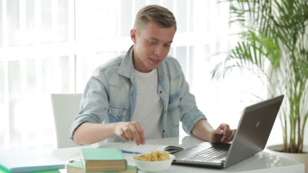 Student siedząc przy stole, przy użyciu laptopa — Wideo stockowe