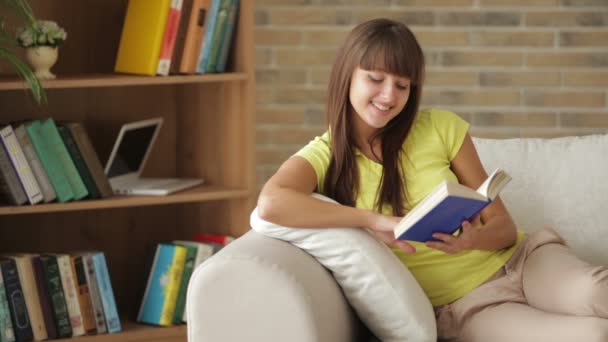 Chica sentada en sofá libro de lectura — Vídeos de Stock