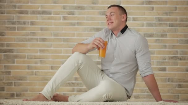 Man zittend op de vloer drinken van SAP — Stockvideo