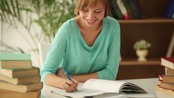 Flickan sitter vid bord studera skriver i anteckningsboken — Stockvideo