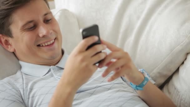 Killen ligger på soffan med mobiltelefon — Stockvideo