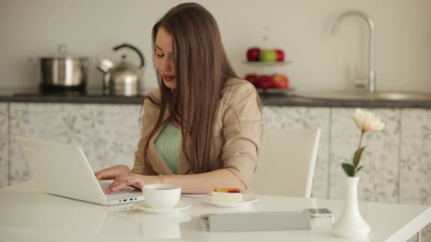 Chica sentada en la mesa usando portátil — Vídeos de Stock