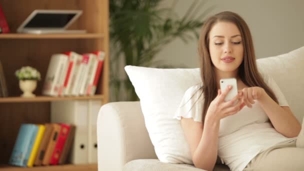 Женщина на диване с помощью мобильного телефона — стоковое видео