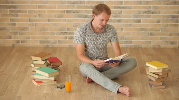 Mann sitzt auf dem Boden und liest Buch — Stockvideo