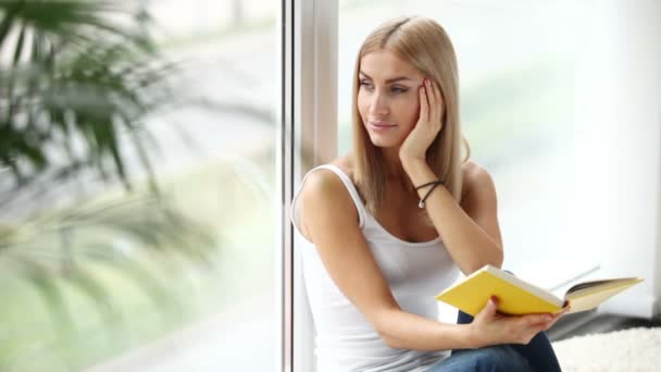 Chica sentado por ventana lectura libro — Vídeo de stock