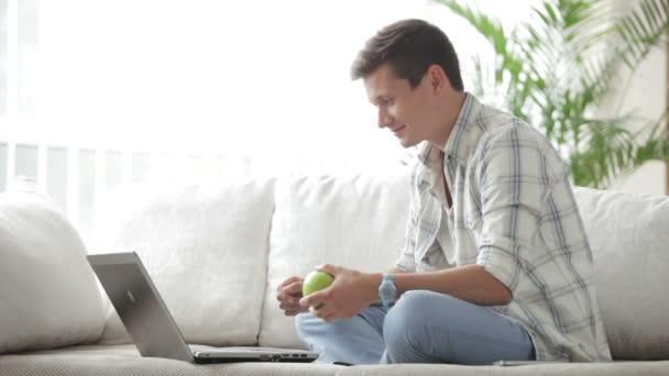 Killen sitter på soffan med laptop — Stockvideo