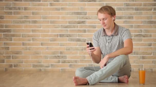 Guy wearing earphones sitting on floor — Stock Video