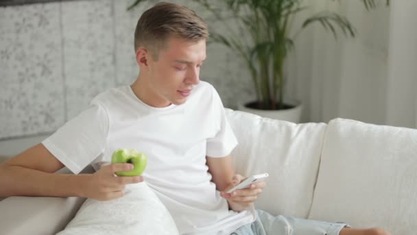 Mann sitzt mit Handy auf Sofa — Stockvideo