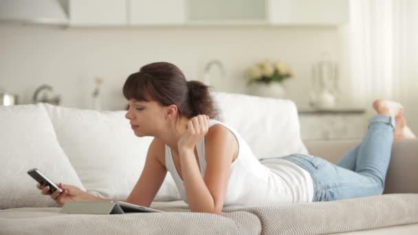 Donna sdraiata sul divano con touchpad — Video Stock