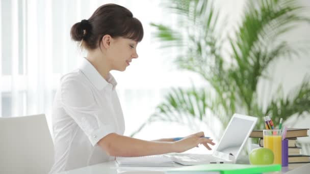 Girl sitting at table using laptop — Stock Video