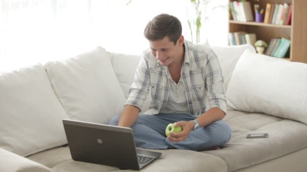 Man ontspannen op de sofa met behulp van laptop — Stockvideo
