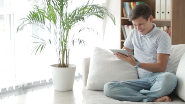 Mann sitzt auf Sofa mit Touchpad — Stockvideo