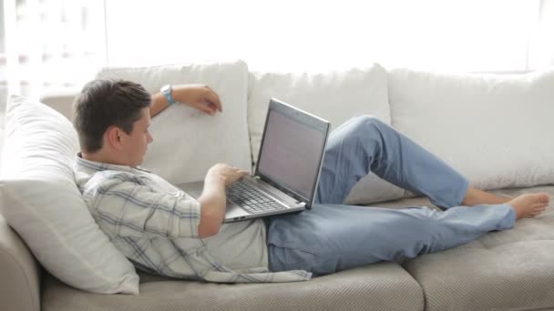 Man lying on couch using laptop — Stock Video