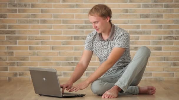 Chlapík sedí na podlaze pomocí přenosného počítače — Stock video