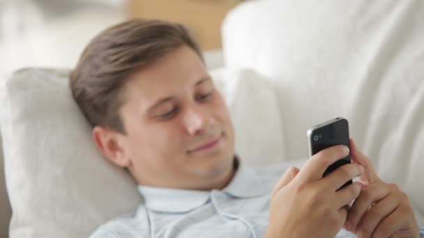 Człowiek na kanapie przy użyciu telefonu komórkowego — Wideo stockowe