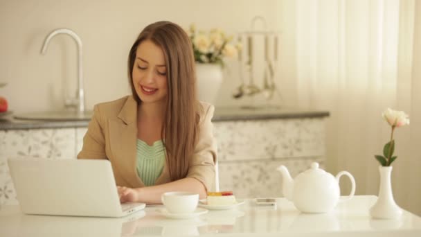 Mujer sentada a la mesa con portátil — Vídeos de Stock