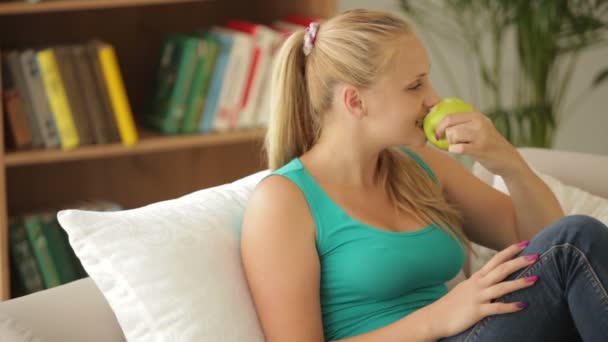 Chica relajante en sofá y comer manzana — Vídeos de Stock