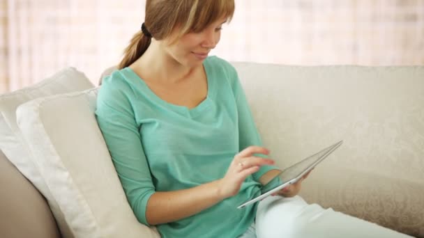 Girl relaxing on couch using touchpad — Stock Video