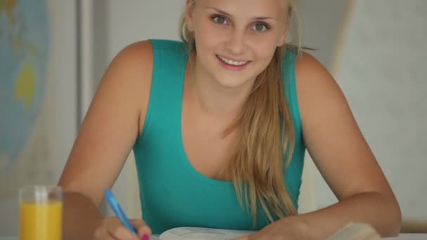 Írás jegyzetfüzet, és mosolyogva a lány — Stock videók