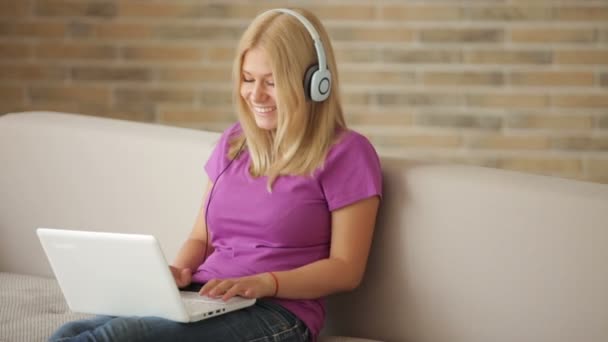 Chica en auriculares usando portátil — Vídeo de stock