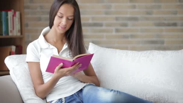 Девушка отдыхает на диване чтение — стоковое видео