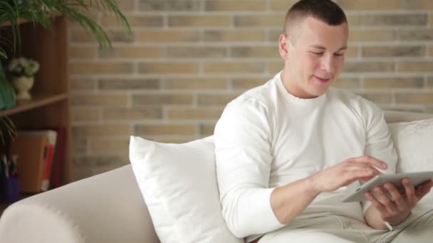 Mann sitzt auf Sofa mit Touchpad — Stockvideo