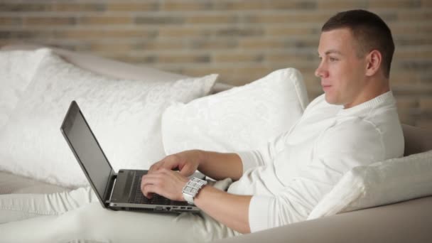 Guy avkopplande soffan med laptop — Stockvideo