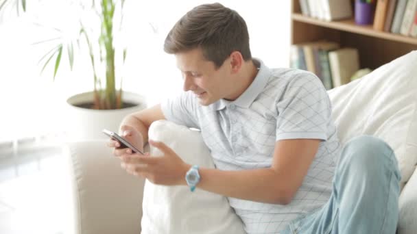 Ο άνθρωπος που κάθεται στον καναπέ χρησιμοποιώντας το κινητό τηλέφωνο — Αρχείο Βίντεο