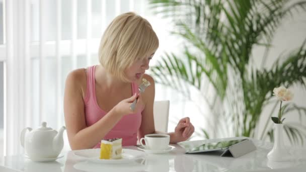 Mujer comiendo pastel usando touchpad — Vídeo de stock