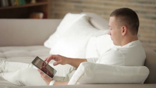 Hombre sentado en el sofá usando touchpad — Vídeo de stock