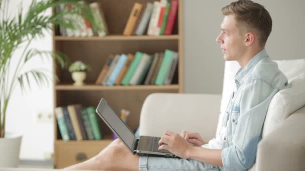 Estudante relaxante no sofá com laptop — Vídeo de Stock