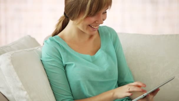 Touchpad kullanarak kanepede oturan kız — Stok video