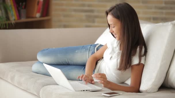 Mädchen entspannt sich auf Couch mit Laptop — Stockvideo