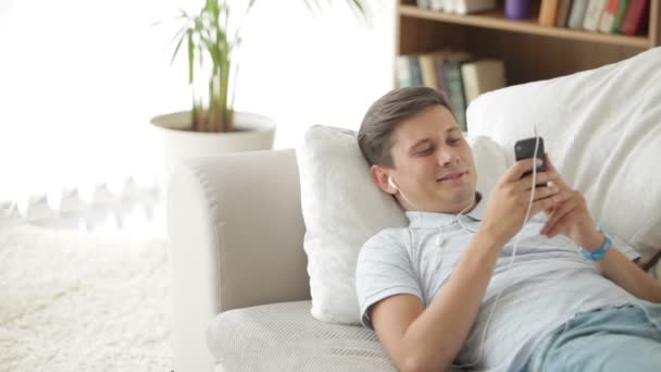 Guy liggend op de Bank luisteren naar muziek — Stockvideo