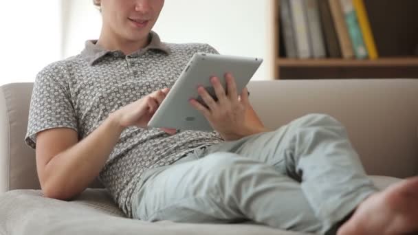 Όμορφος άντρας κάθεται στον καναπέ χρησιμοποιώντας touchpad — Αρχείο Βίντεο