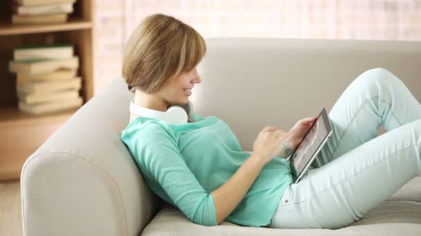 Menina relaxante no sofá usando touchpad — Vídeo de Stock