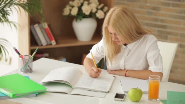 Girl sitting at desk writing — Stock Video