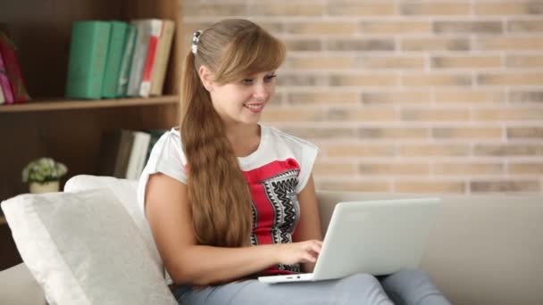 Menina sentada no sofá usando laptop — Vídeo de Stock