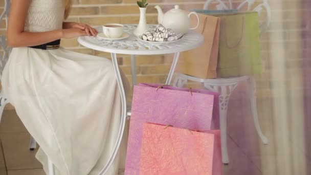 Alışveriş torbaları ile kafede oturan kız — Stok video