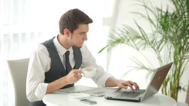 Hombre sentado en la mesa usando el ordenador portátil — Vídeos de Stock