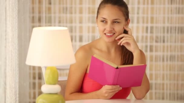 Niña sentada en la mesa en el café libro de lectura — Vídeos de Stock