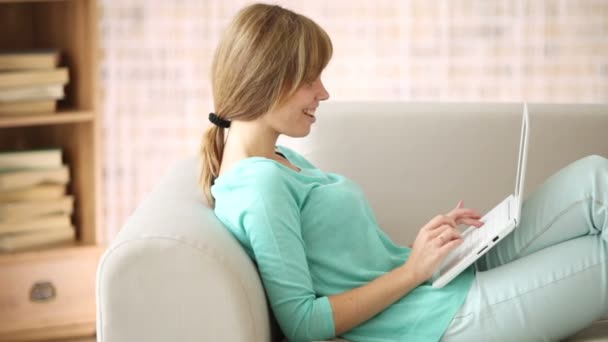 Menina relaxante no sofá usando laptop — Vídeo de Stock