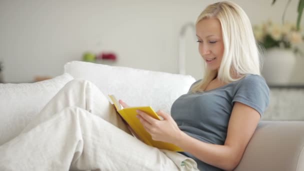 Mujer sentada en el sofá libro de lectura — Vídeo de stock