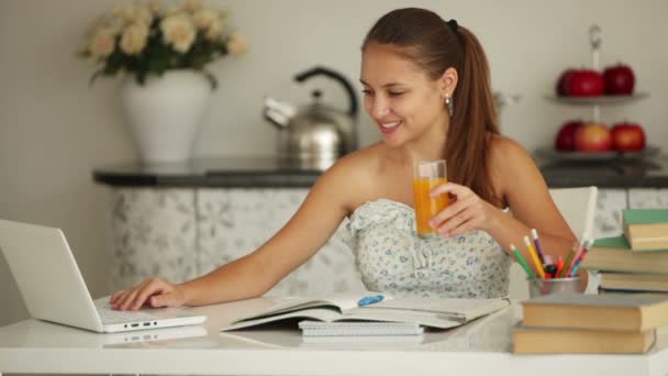 Girl sitting at table studying with laptop — Stock Video