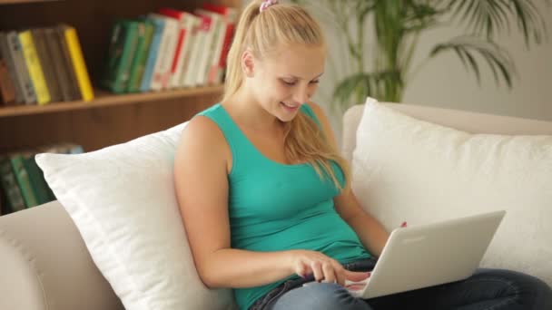 Meisje, zittend op de Bank met behulp van laptop — Stockvideo