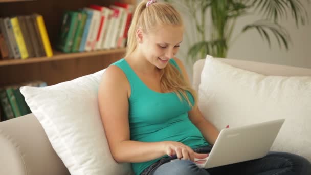 Ragazza seduta sul divano utilizzando il computer portatile — Video Stock