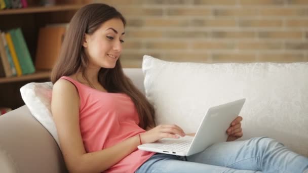 Meisje ontspannen op de sofa met behulp van laptop — Stockvideo